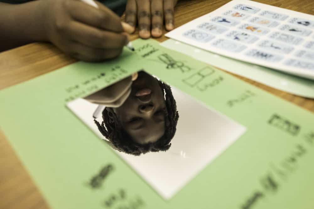 Marco Colesis is reflected in a values mirror project. // University of Rochester student volunteers for Eye to Eye, a national non-profit organization that pairs neurodivergent middle school students with learning and attention differences with college and high school students who share similar labels, work with students at Rochester Prep in Rochester, NY April 2, 2025.  // photo by J. Adam Fenster / University of Rochester